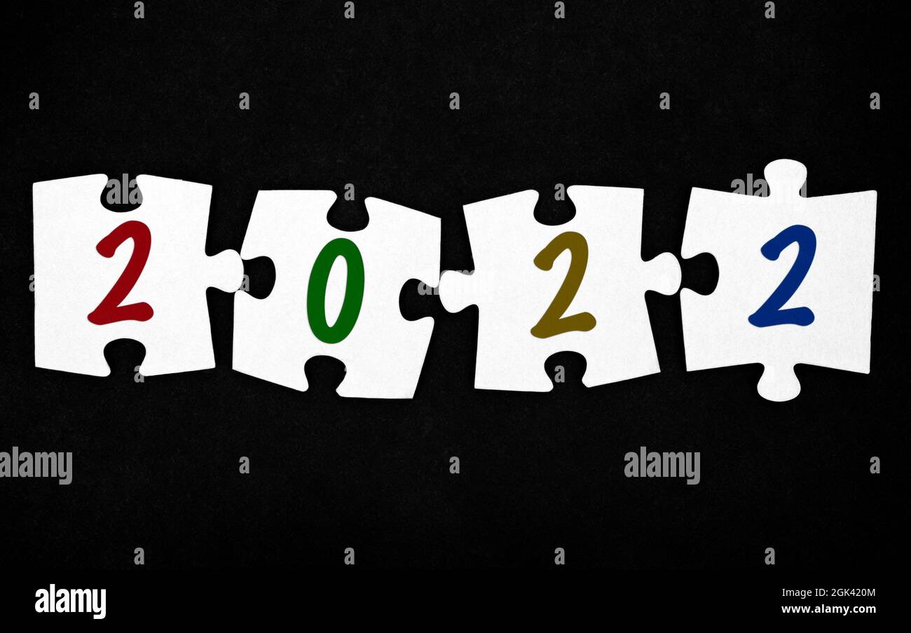 Quattro pezzi di puzzle con numeri 2022 su sfondo nero. Primo piano. Foto Stock