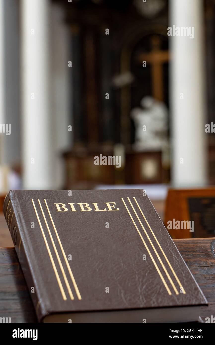 La Bibbia sulla tavola di una panchina di preghiera nella chiesa con un altare. Foto Stock