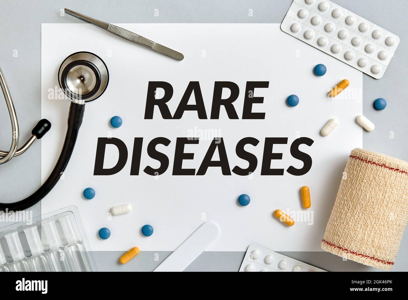 Malattie rare, concetto medico circondato da pillole e forniture mediche su sfondo grigio. Vista dall'alto. Foto Stock