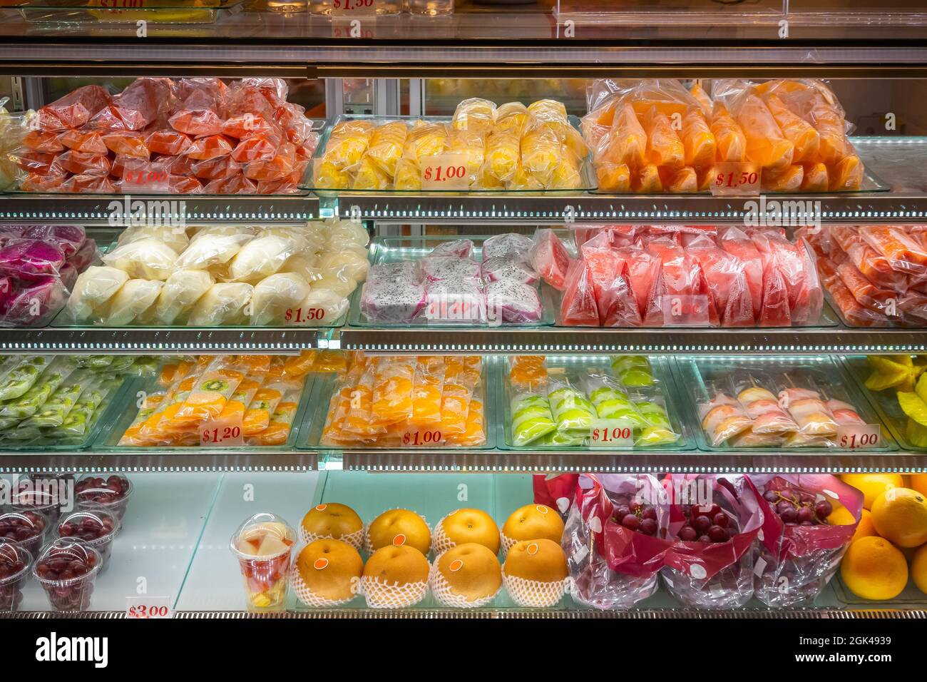Varietà di frutta tropicale in fette in mostra in un frigorifero in mostra presso un negozio di alimentari a Singapore Foto Stock