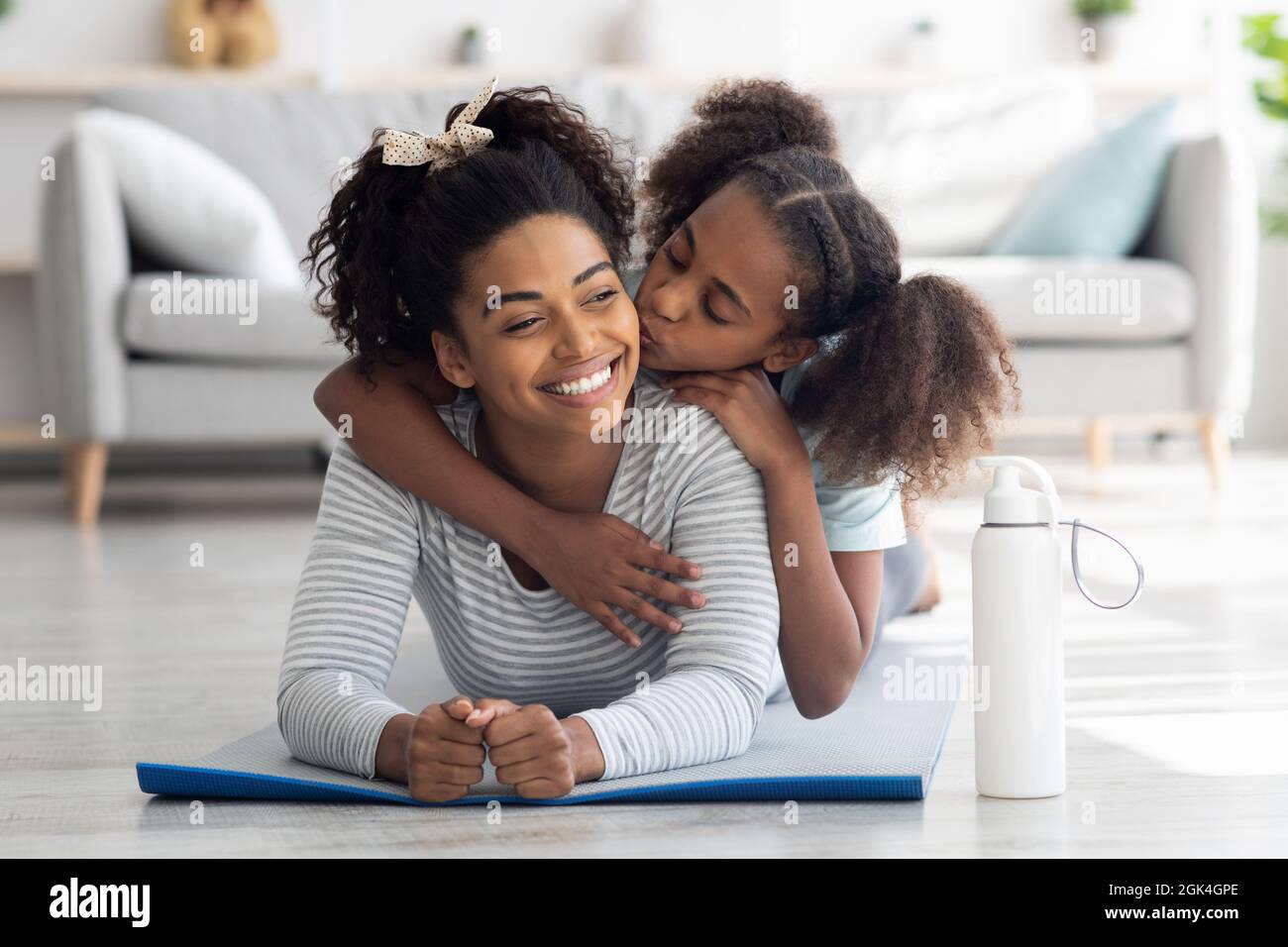 Buona madre nera e figlia coccolarsi mentre praticano lo yoga Foto Stock