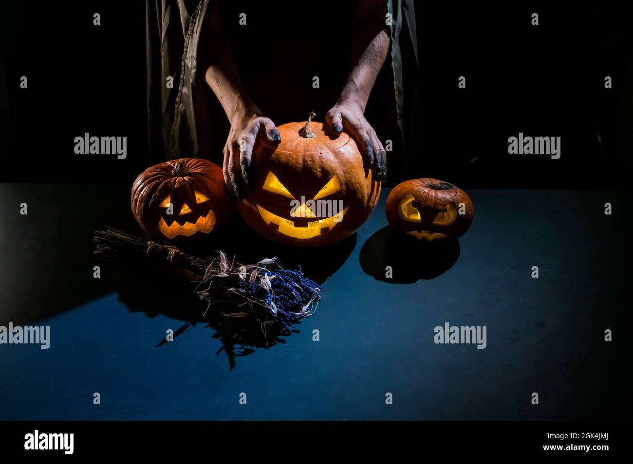 Primo piano delle mani femminili che tengono una zucca di Halloween nel buio Foto Stock