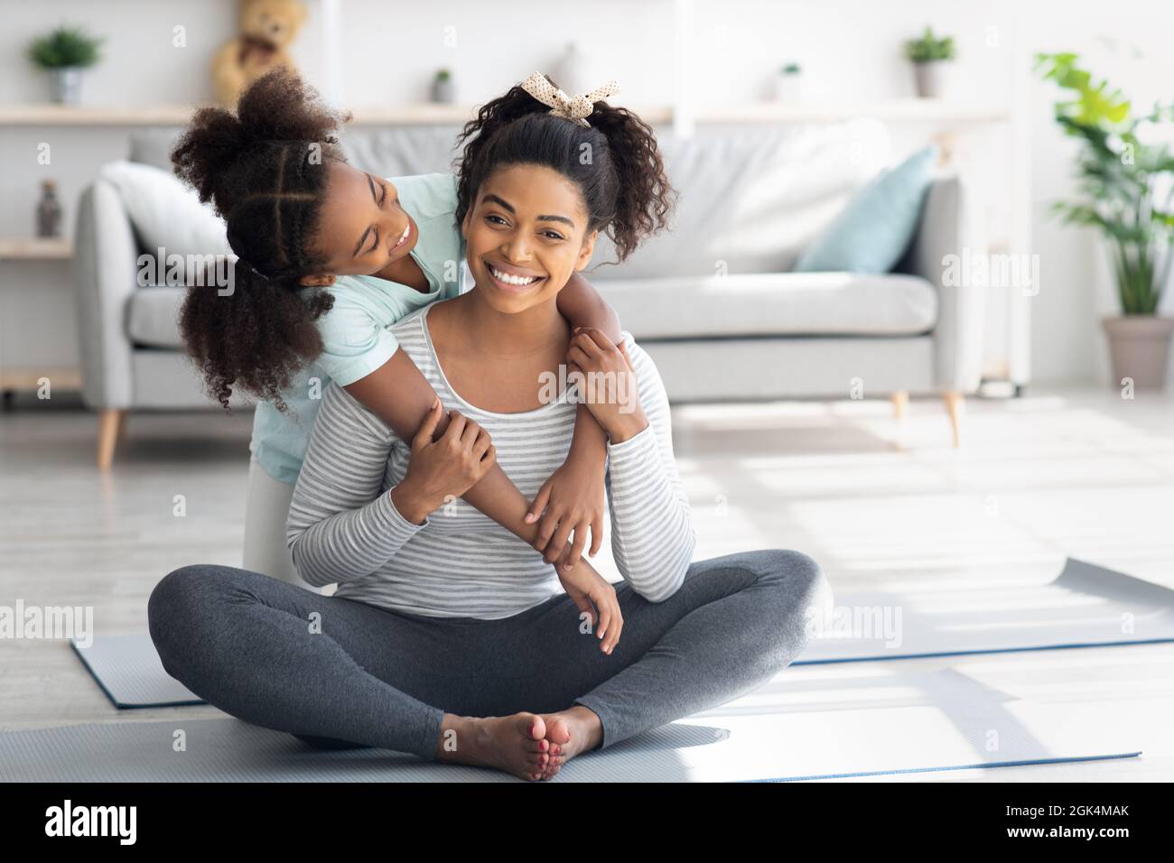 Bella madre nera e figlia coccolare mentre si esercita Foto Stock