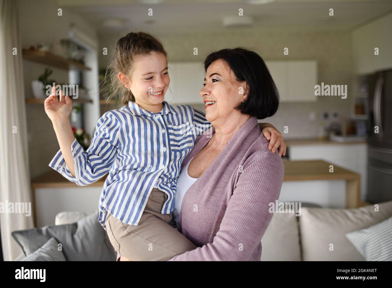 Piccola ragazza felice con nonna senior al coperto a casa divertirsi. Foto Stock