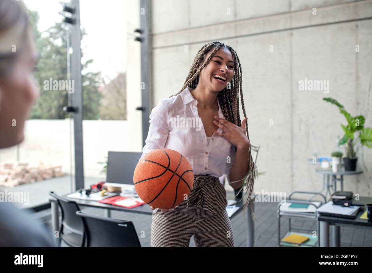Giovane donna d'affari allegra divertirsi con la palla in ufficio, prendere un concetto di pausa. Foto Stock