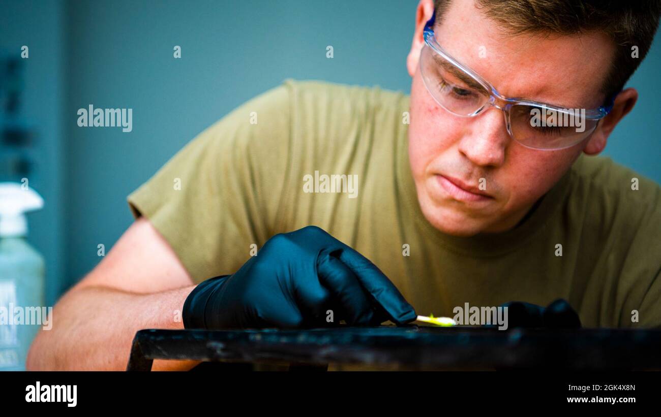 US Air Force Senior Airman Maverick Shuler, 380esimo specialista di ispezione non distruttiva Squadron Expeditionary Maintenance, applica il penetrante florescente a un oggetto metallico presso la base aerea al Dhafra, Emirati Arabi Uniti, 2 agosto 2021. Il penetrante florescente permise a Shuler di ispezionare meglio l'oggetto per verificare la presenza di crepe, ammaccature e imperfezioni. Foto Stock