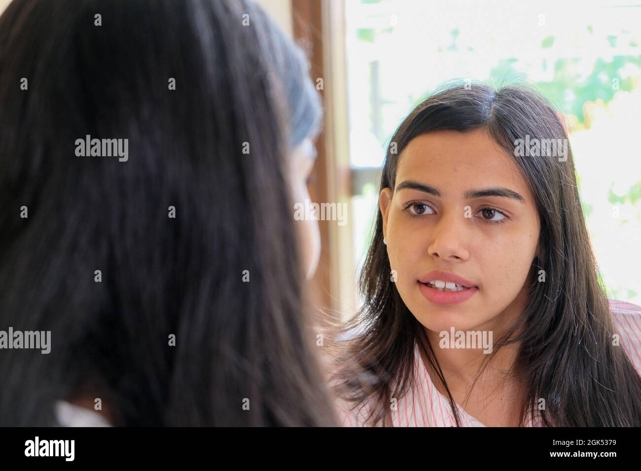 Primo piano girato del volto di una giovane ragazza durante la conversazione Foto Stock