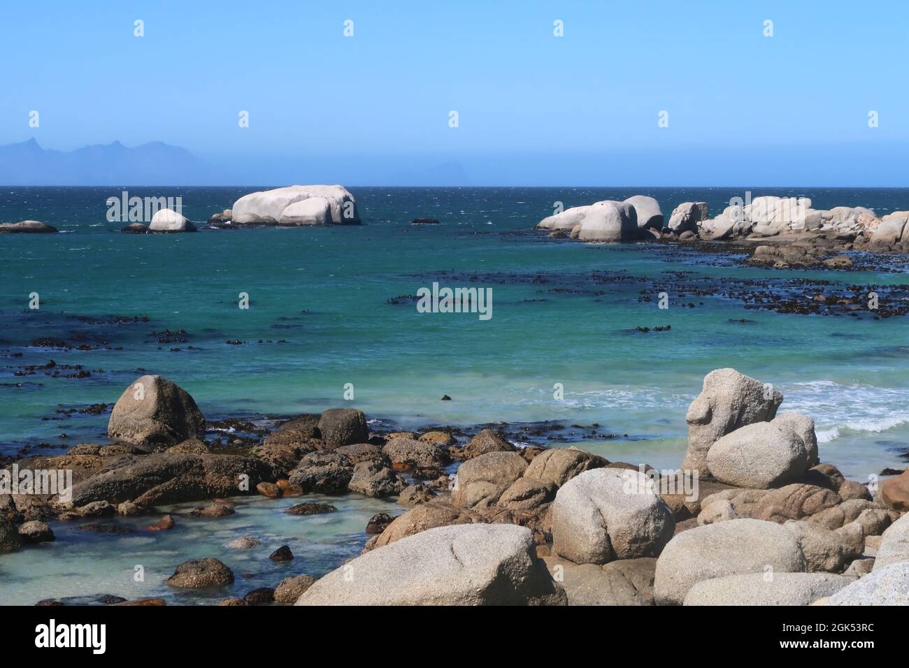 Scenografica acque turchesi dell'oceano Indiano lungo la spiaggia sabbiosa con grandi massi di granito vicino alla città di Simons, sulla Penisola del Capo, Città del Capo, Sudafrica Foto Stock