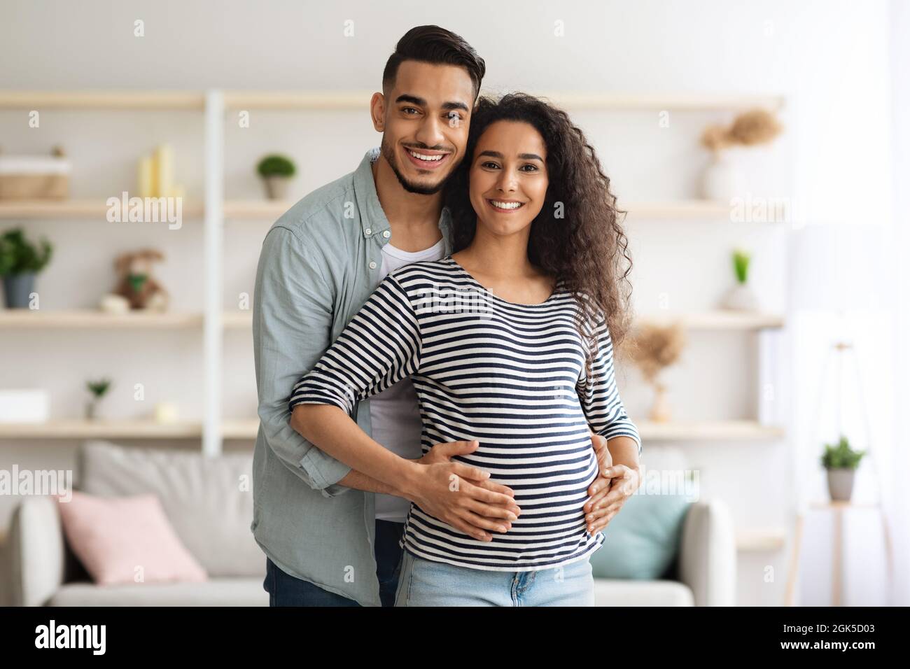 Felice uomo medio-orientale abbracciando la sua bella moglie incinta, in posa insieme Foto Stock