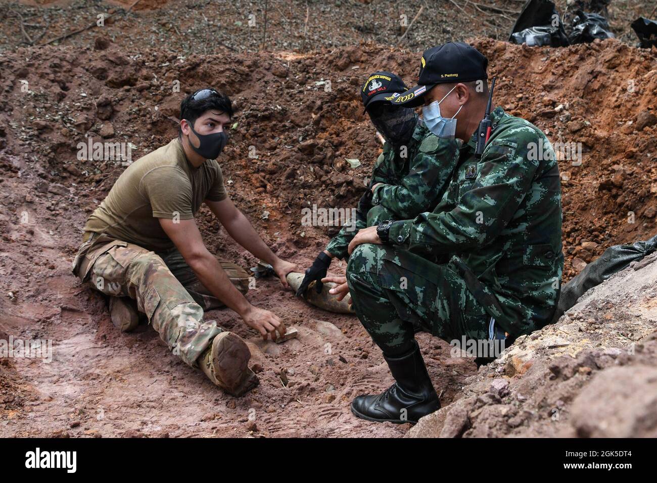 U.S. Air Force staff Sgt. Justin Campos, a sinistra, lavora con Royal Thai Army Sergeants Major 1st Class Panupong Phongam, Center, e Supalerk Panthong, a destra, per disporre l'ordigno inesploso per la detonazione su larga scala a Ta Mor Roi area di addestramento durante l'esercizio Cobra Gold 21 nella Provincia di Surin, Thailandia, 6 agosto 2021. Royal Thai e American Armed Forces hanno lavorato insieme durante l'esercizio per condurre operazioni di smaltimento delle mine terrestri, formazione sulla procedura di render-safe, e formazione in coppia sulla risposta medica trauma. Questo esercizio è in linea con il Prog di azione per la miniera umanitaria del Dipartimento della Difesa degli Stati Uniti Foto Stock