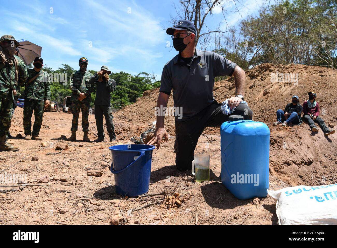 James Shelstad, consulente tecnico per lo smaltimento di ordigni esplosivi presso la Golden West Humanitarian Foundation, Spiega ai membri del servizio Royal Thai e degli Stati Uniti come creare un esplosivo binario liquido per la detonazione di un round di artiglieria al fosforo bianco da 155 millimetri durante l'esercizio Cobra Gold 21 presso l'area di addestramento Ta Mor Roi nella Provincia di Surin, Thailandia, 8 agosto 2021. Royal Thai e American Armed Forces hanno lavorato insieme durante l'esercizio per condurre operazioni di smaltimento delle mine terrestri, formazione sulla procedura di render-safe, e formazione in coppia sulla risposta medica trauma. Questo esercizio è allineato wi Foto Stock