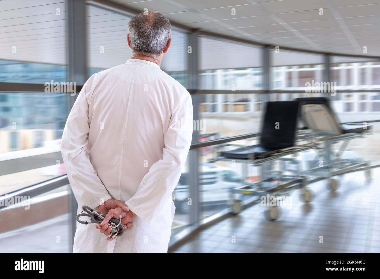 Concetto di medicina e assistenza sanitaria - il medico che cammina lungo il corridoio ospedaliero mani sul retro stetoscopio di tenuta Foto Stock