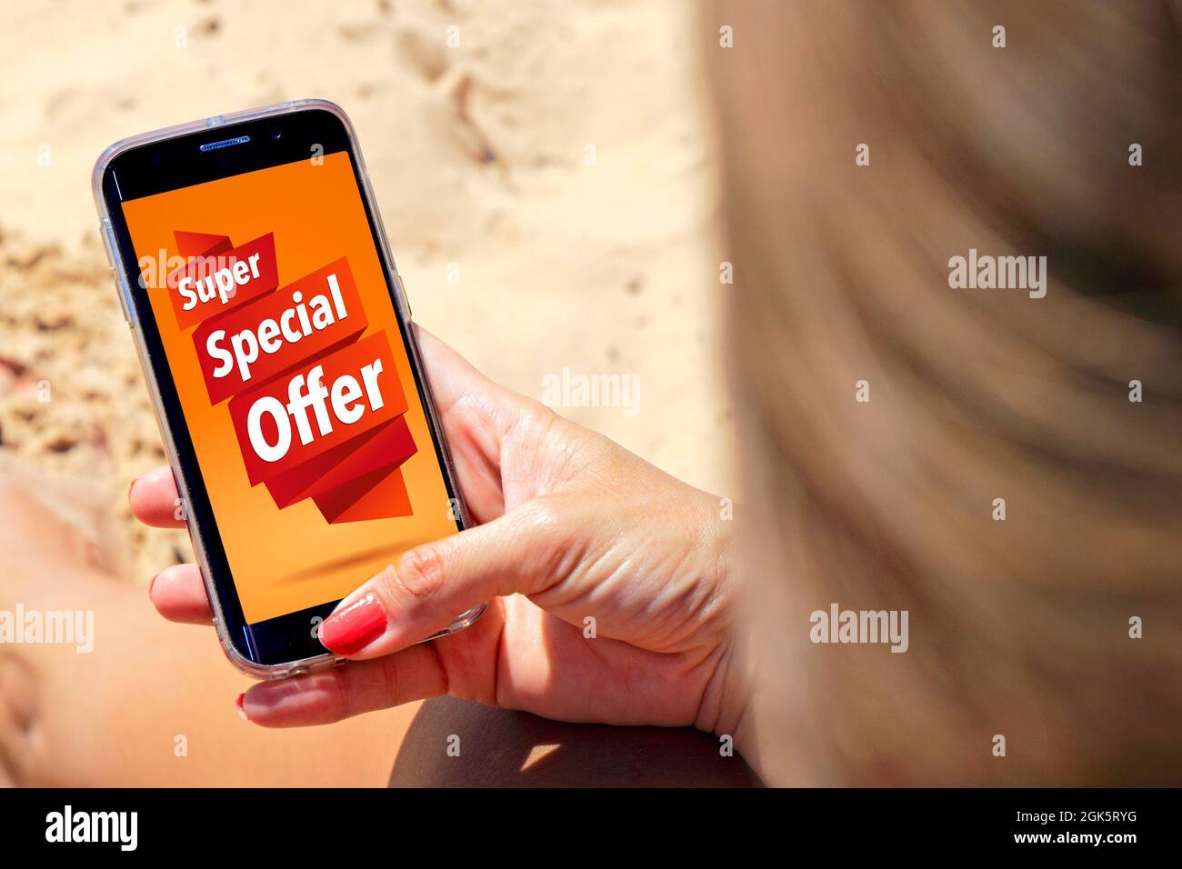 Offerta speciale di pubblicità sul telefono cellulare. Donna sulla spiaggia con uno smartphone nelle mani. Marketing, e-commerce, pubblicità. Foto Stock