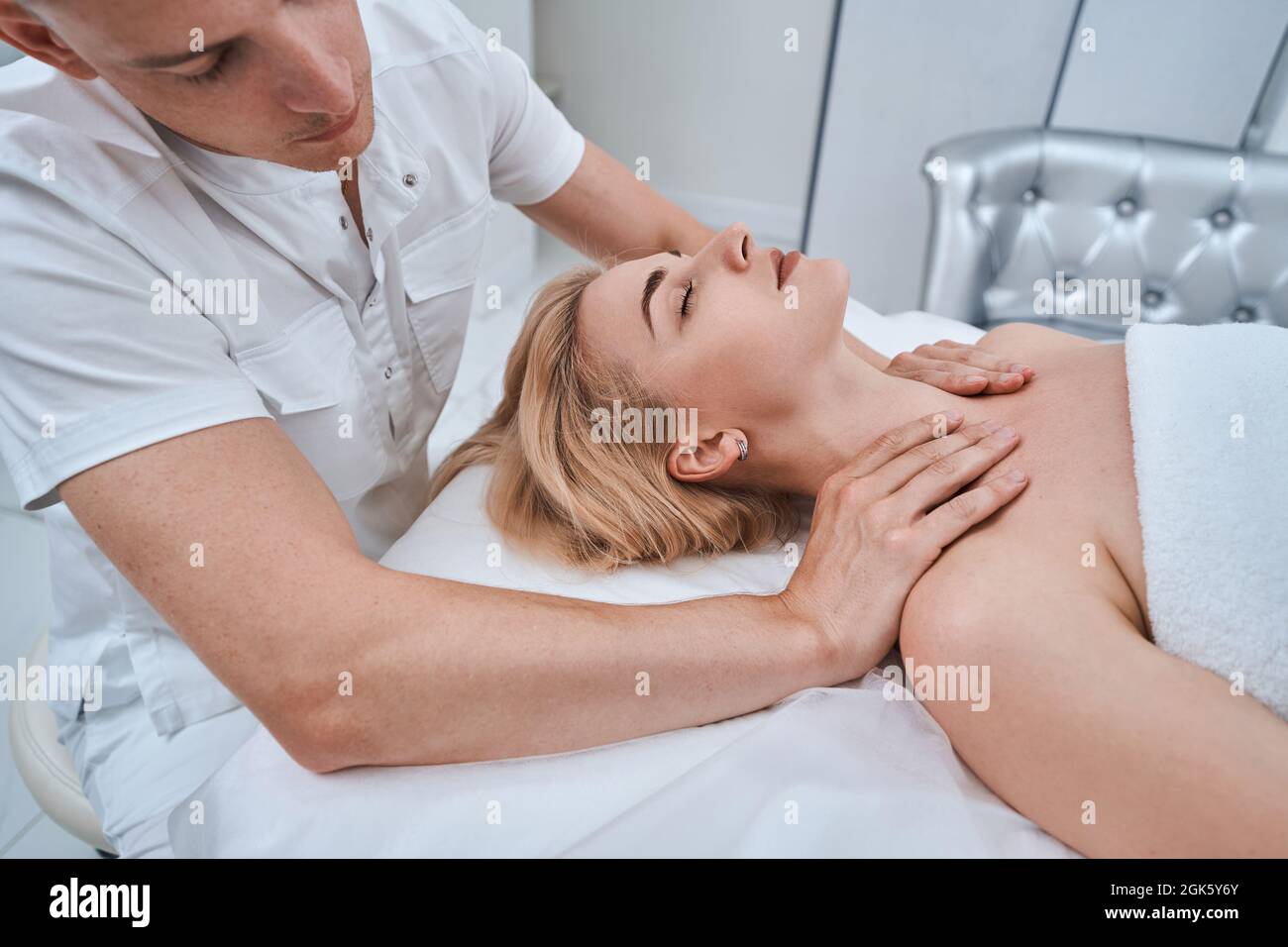 Fisioterapista esperto che dà un massaggio riflessologico ad una giovane donna Foto Stock