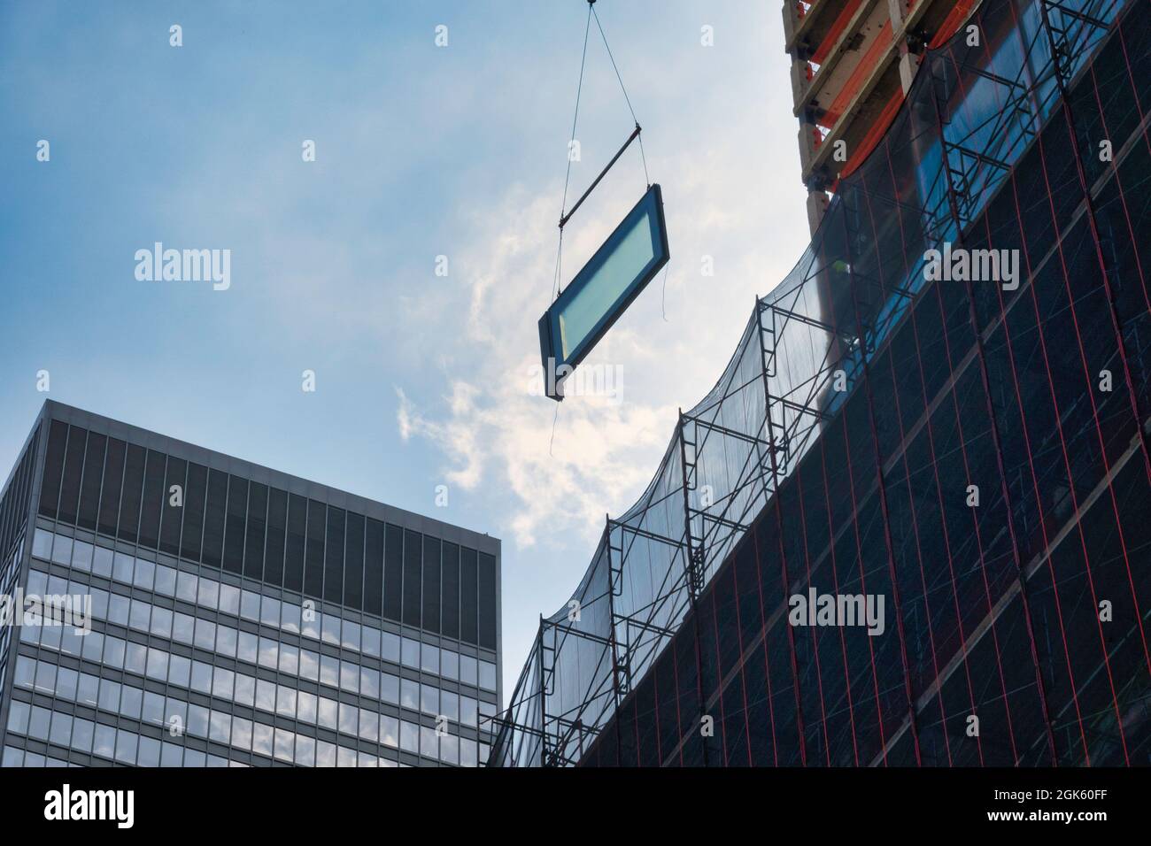 Gru da cantiere che guida un gigantesco vetro del vetro per l'installazione in un grattacielo sulla Fifth Avenue, New York City, USA 2021 Foto Stock