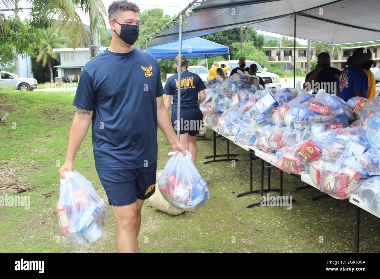 AGAT, Guam (agosto 13, 2021) - i marinai di USS Emory S. Land (AS 39) e Visiting Marines of Combat Logistics Regiment 17 (CLR-17) si sono offerti volontariamente all’Ufficio del Sindaco di Agat per distribuire 400 pacchetti di prodotti alimentari nell’ambito del programma di assistenza alimentare d’emergenza (TEFAP), agosto 12. Le materie prime sono rese possibili attraverso il Guam Department of Education attraverso il Dipartimento dell'Agricoltura degli Stati Uniti Food Nutrition Service e sono distribuite dai sindaci del villaggio a famiglie bisognose e colpite dalla pandemia COVID-19. Il 9 agosto, volontari del Land e CLR 17 hanno confezionato le 400 confezioni di cibo Foto Stock