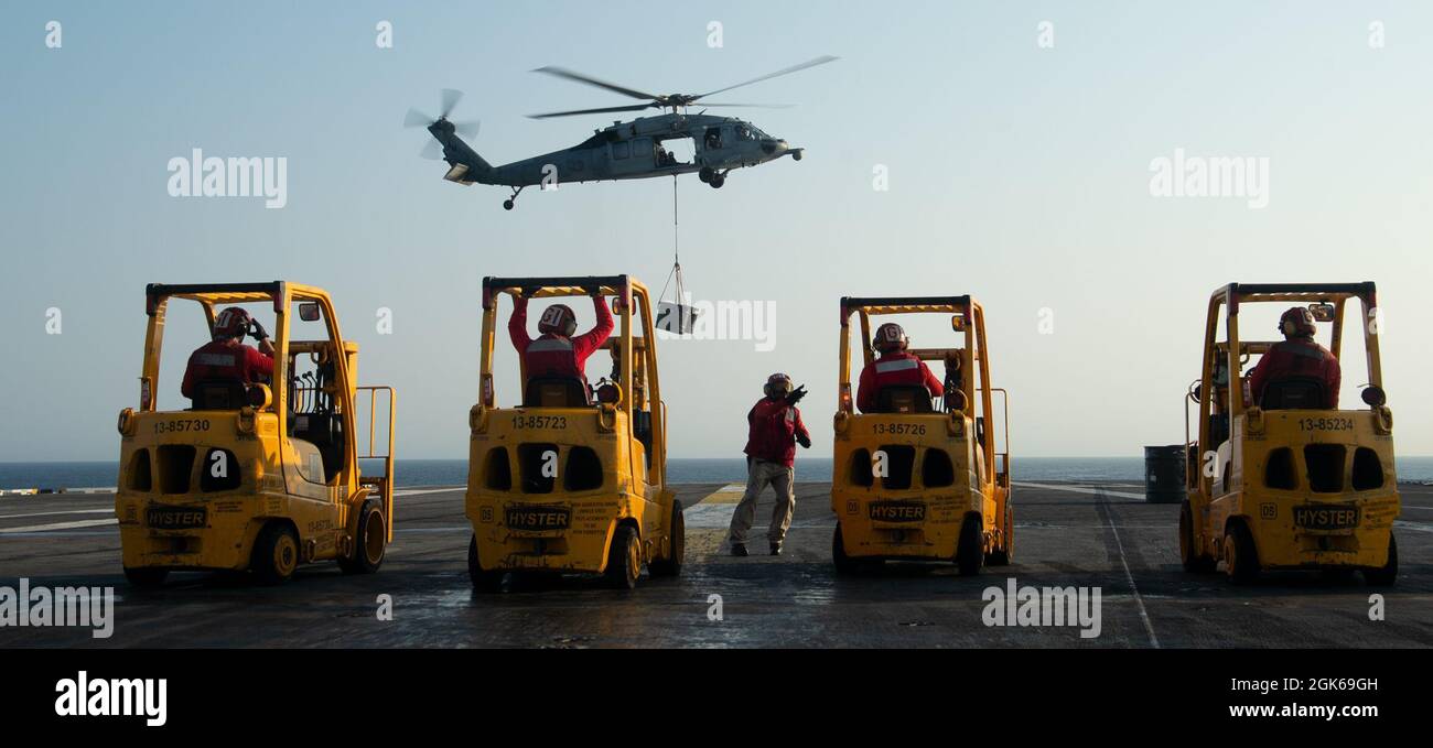 210813-N-PG226-1064 OCEANO ATLANTICO (AGOSTO 13, 2021) un elicottero MH-60S Sea Hawk, attaccato al 'Cavalieri di Squadrone di combattimento del Mare dell'elicottero (HSC) 22, trasporta il carico al ponte di volo della portaerei di classe Nimitz USS Harry S. Truman (CVN 75). Truman sta conducendo corsi di preparazione per le operazioni future nell'Oceano Atlantico. Foto Stock