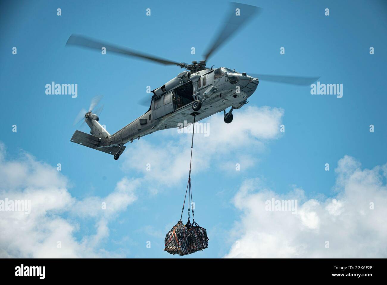 OCEANO PACIFICO (19 aprile 2021) Un falco marino MH-60S della Marina degli Stati Uniti assegnato a Elicotteri Sea Combat Squadron 4 la cinghia carica il carico durante un rifornimento verticale-a-mare con il bacino di trasporto anfibio USS Portland (LPD 27), agosto 14. Marines e marinai dell'XI MEU e Essex Amphibious Ready Group (ARG) stanno conducendo operazioni di routine nella terza flotta statunitense. Foto Stock