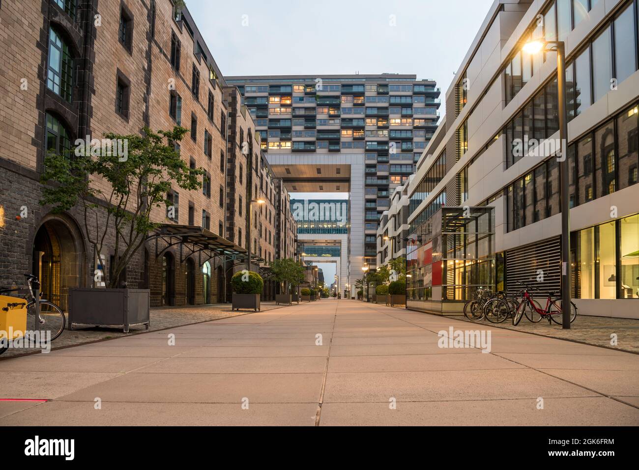 Magazzini in mattoni rinnovati insieme a un moderno edificio residenziale e di uffici su una banchina lungo un fiume in una notte estiva. Foto Stock