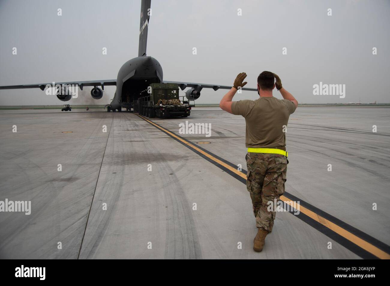 Personale dell'aeronautica degli Stati Uniti. SGT. Logan Williford, 366th Logistics Readiness Squadron Air Transportation Supervisor, dirige un pilota di Tuner 60K in appoggio dalla base di un C-17 Globemaster III alla base dell'aeronautica militare di Mountain Home, Idaho, 16 agosto 2021. Il veicolo con sintonizzatore 60K viene utilizzato per trasportare carichi di grandi dimensioni da un aeromobile C-17. Foto Stock