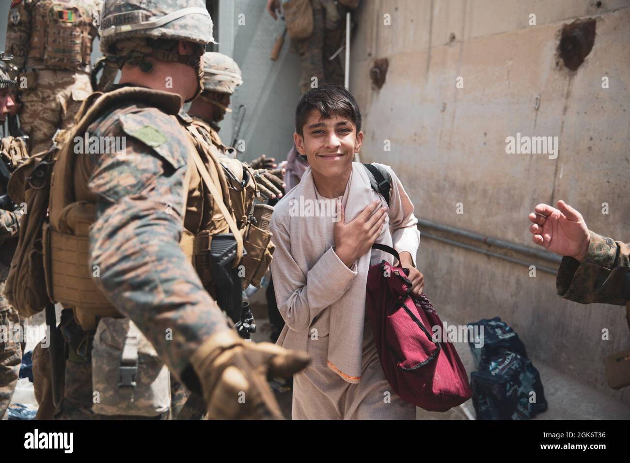 Un ragazzo viene processato attraverso un Evacuee Control Checkpoint (ECC) durante un'evacuazione all'Aeroporto Internazionale Hamid Karzai, Kabul, Afghanistan, 18 agosto. I Marines degli Stati Uniti stanno assistendo il Dipartimento di Stato con un prelievo ordinato di personale designato in Afghanistan. Foto Stock