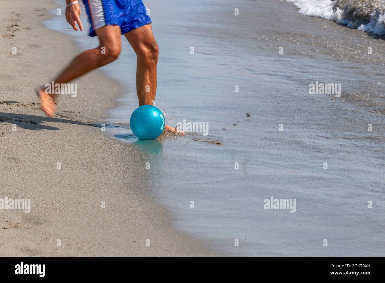 Le gambe di un uomo che gioca a calcio sulla riva della spiaggia di Marina di Carrara, Toscana, Italia Foto Stock