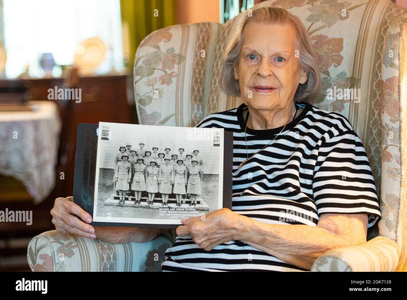 Lorraine Vogelsang, veterano del corpo dell'Esercito delle Donne, si pone con una foto di lei e dei suoi compagni di classe della Bakers and Cooks School di Fort Oglethorpe, Georgia, all'interno di sua Cincinnati, Ohio, casa, 19 agosto 2021. Vogelsang ha servito nel WAC da febbraio 1943 ad agosto 1945. Foto Stock