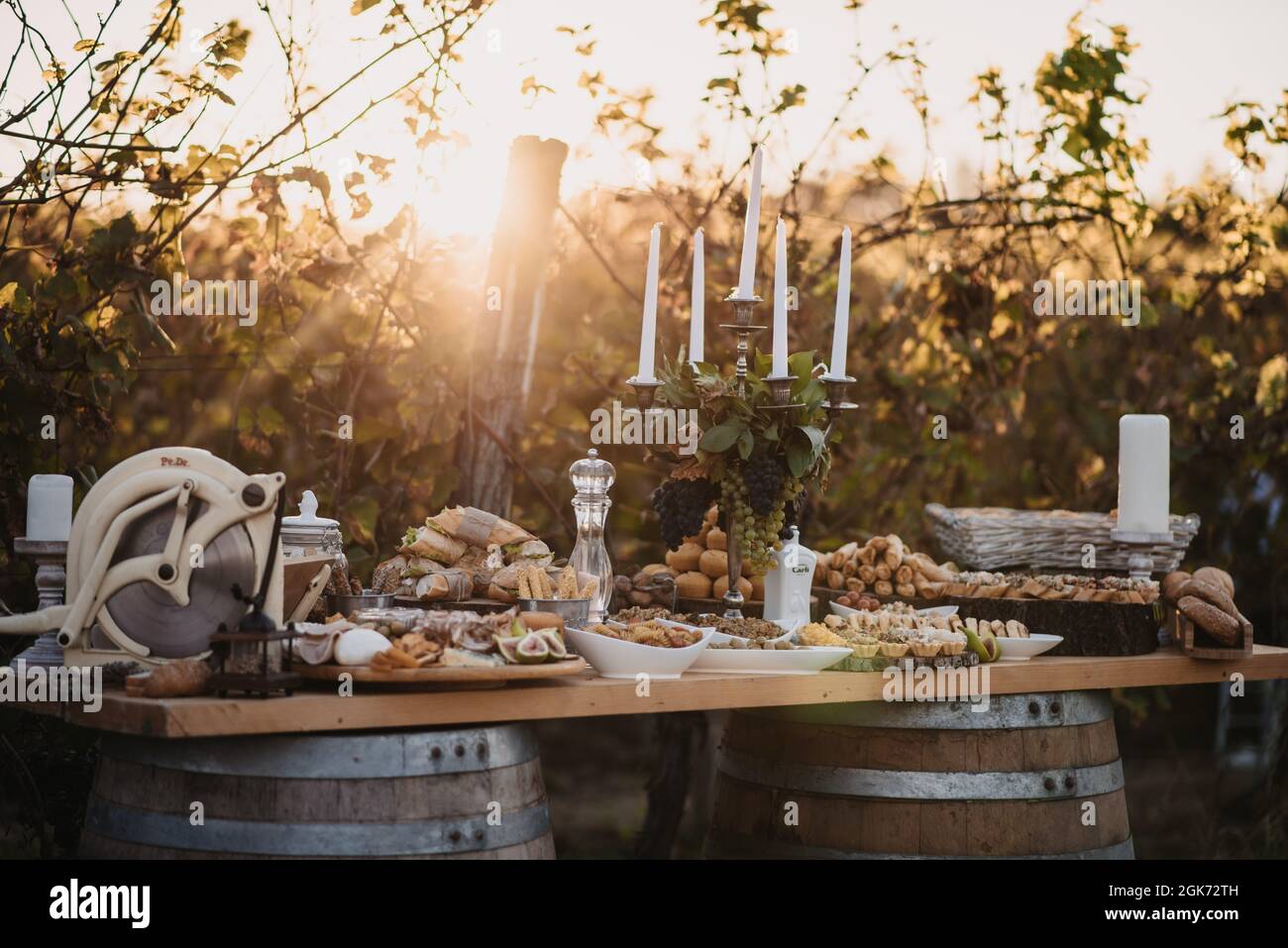Primo piano di un tavolo in legno sulle botti con diversi tipi di cibo e portacandele. Foto Stock