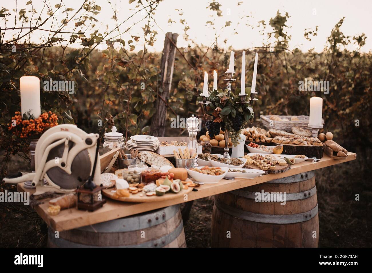 Tavolo in legno sulle botti con diversi tipi di cibo e un portacandele. Foto Stock