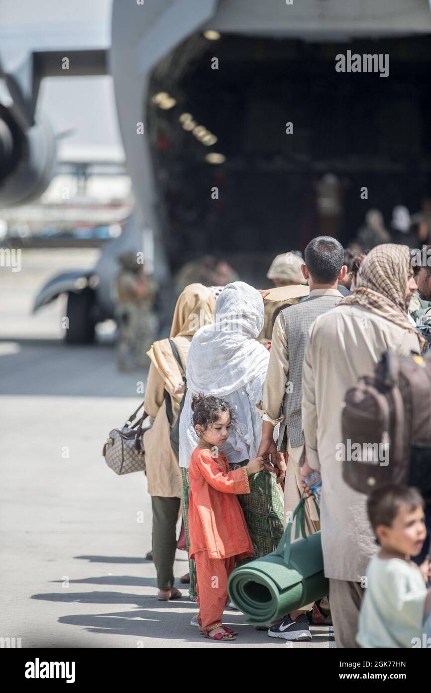 Le famiglie aspettano di salire a bordo di un Boeing dell'aeronautica statunitense C-17 Globemaster III durante un'evacuazione all'aeroporto internazionale Hamid Karzai, Kabul, Afghanistan, 22 agosto. I membri del servizio degli Stati Uniti stanno assistendo il Dipartimento di Stato con un prelievo ordinato di personale designato in Afghanistan. Foto Stock
