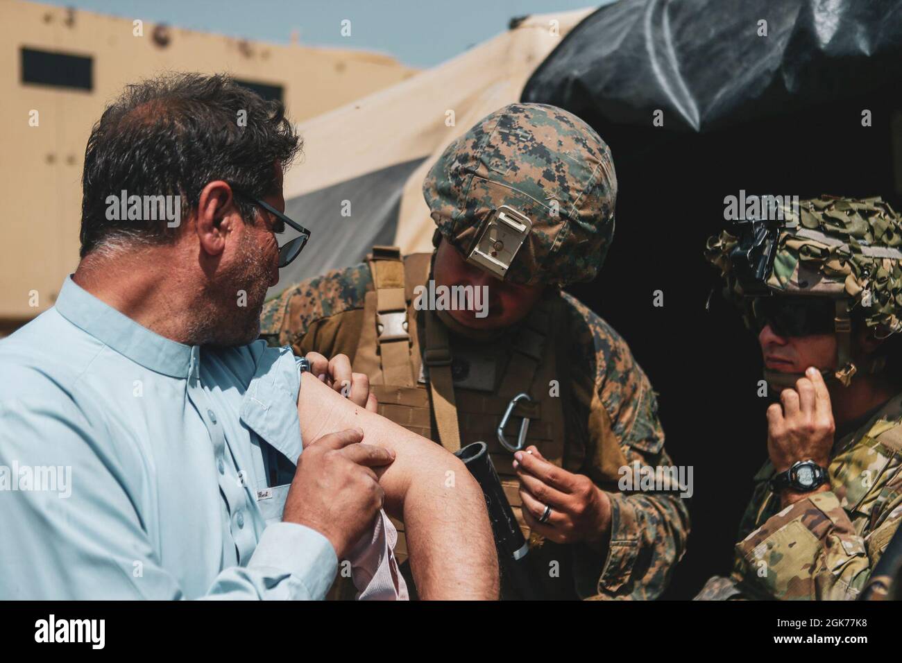 Un Corpsman assegnato alla 24a unità Marine Expeditionary (MEU) e un medico assegnato alla 82a Divisione Airborne assiste un evacuatore durante un'evacuazione all'Aeroporto Internazionale Hamid Karzai, Kabul, Afghanistan, 22 agosto. I membri del servizio degli Stati Uniti stanno assistendo il Dipartimento di Stato con un'operazione DI evacuazione non combattente (NEO) in Afghanistan. Foto Stock