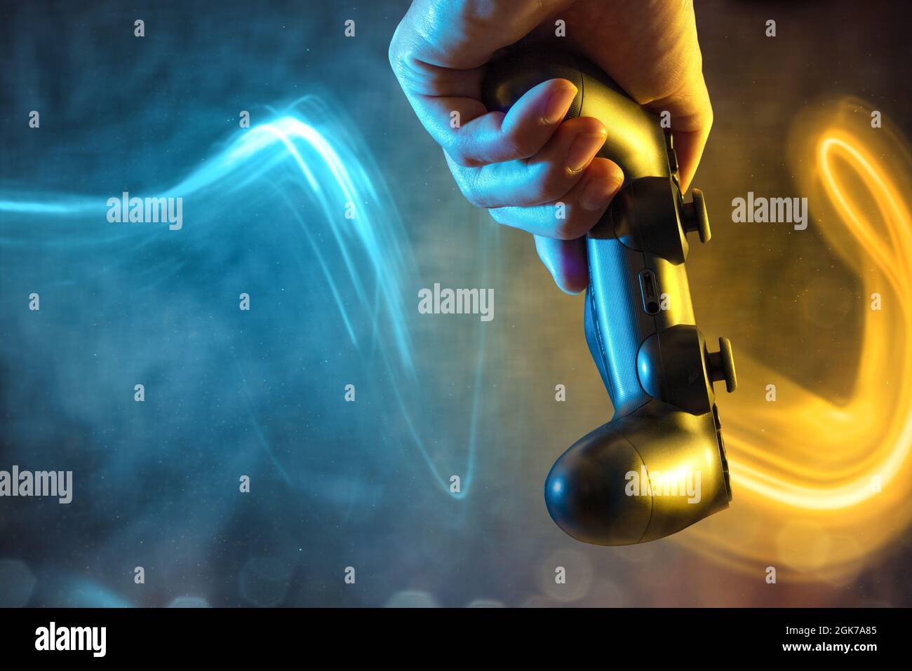 Controller di gioco tenuto da una mano con effetti luminosi colorati Foto Stock