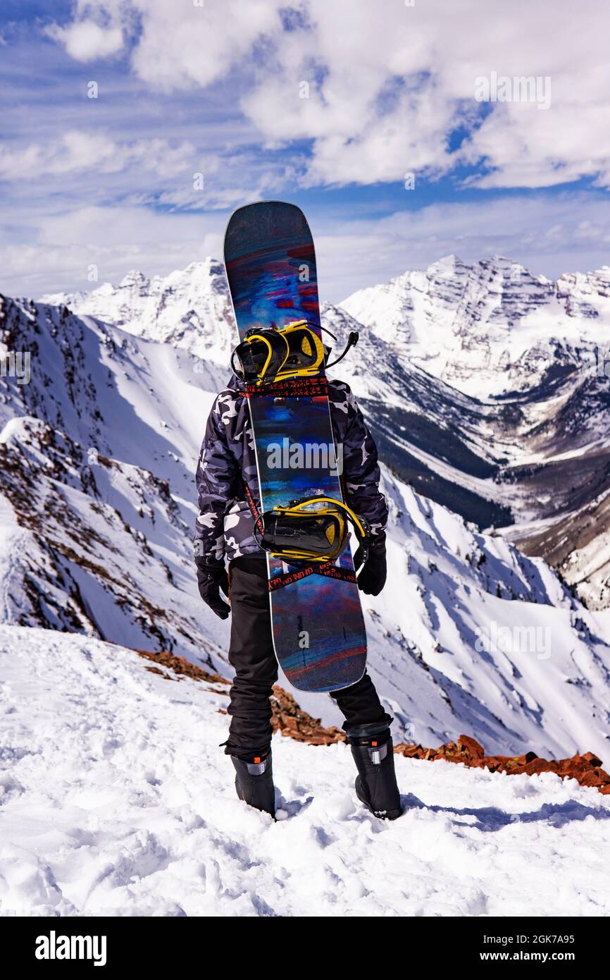 Persona con Snowboard sul retro guardando sopra Mountain Snow Summit Peaks Winter Sports Concept Foto Stock