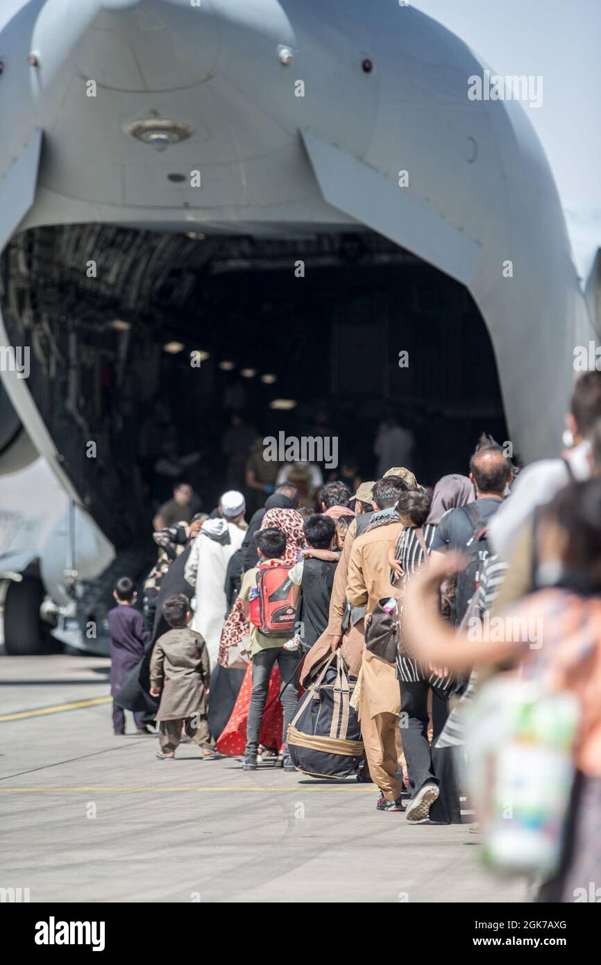 Le famiglie si imbarcaranno su un Boeing dell'aeronautica statunitense C-17 Globemaster III durante un'evacuazione all'aeroporto internazionale Hamid Karzai, Kabul, Afghanistan, agosto 24. I membri del servizio degli Stati Uniti stanno assistendo il Dipartimento di Stato con un prelievo ordinato di personale designato in Afghanistan. Foto Stock