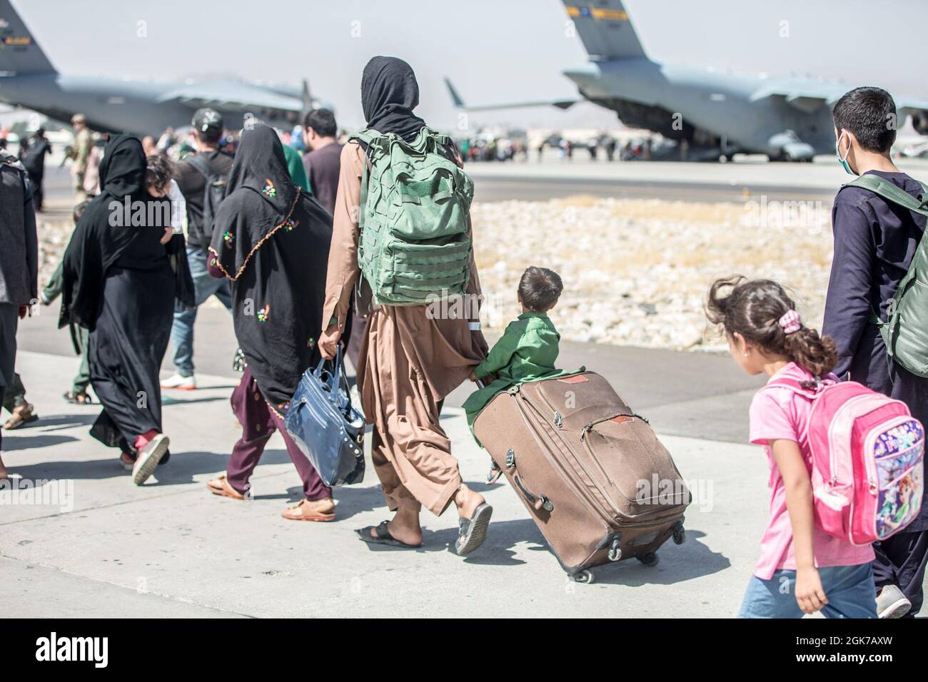 Un bambino guarda il velivolo mentre viene fatto un giro verso il suo volo durante un'evacuazione all'Aeroporto Internazionale Hamid Karzai, Kabul, Afghanistan, 24 agosto. I membri del servizio degli Stati Uniti stanno assistendo il Dipartimento di Stato con un prelievo ordinato di personale designato in Afghanistan. Foto Stock