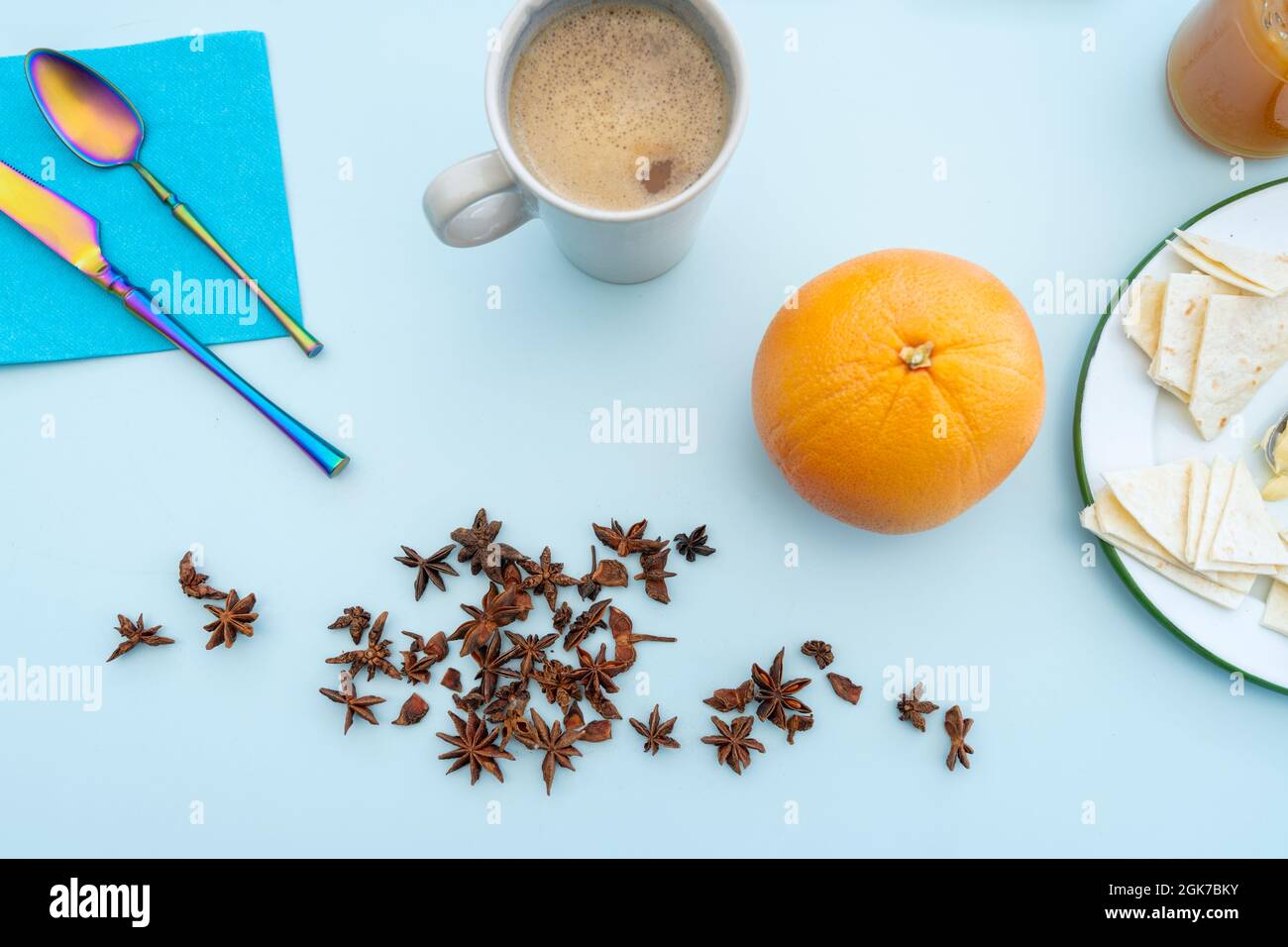 colazione sana con anice, caffè con latte d'avena, pompelmo maturo, cucchiai e forchette e pane acimo su tavola blu Foto Stock