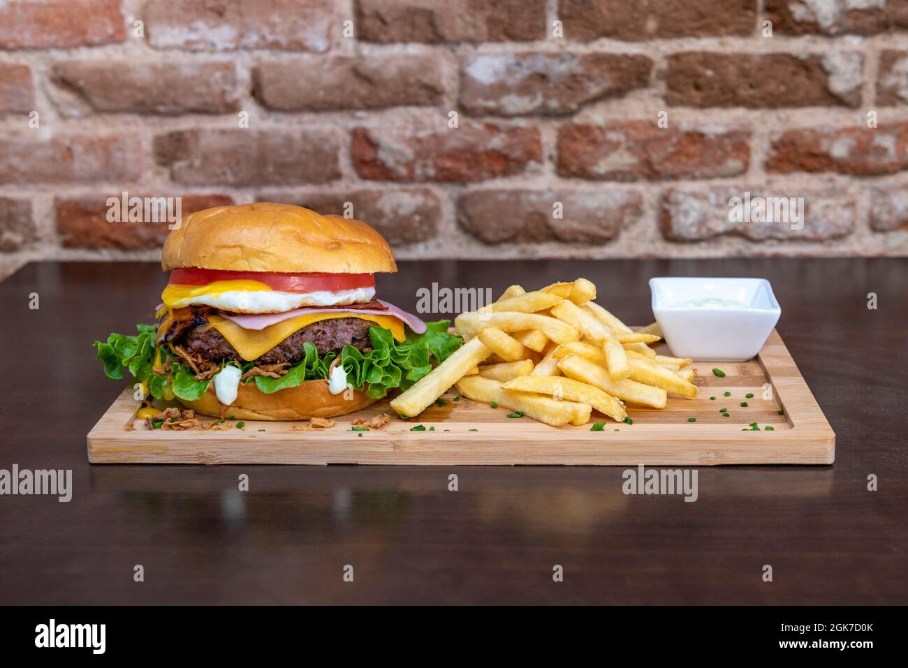 Hamburger con strato di pomodoro, un altro di uova fritte, prosciutto, formaggio cheddar fuso, filetto di manzo, cipolla croccante, lattuga verde e maionese con garni Foto Stock