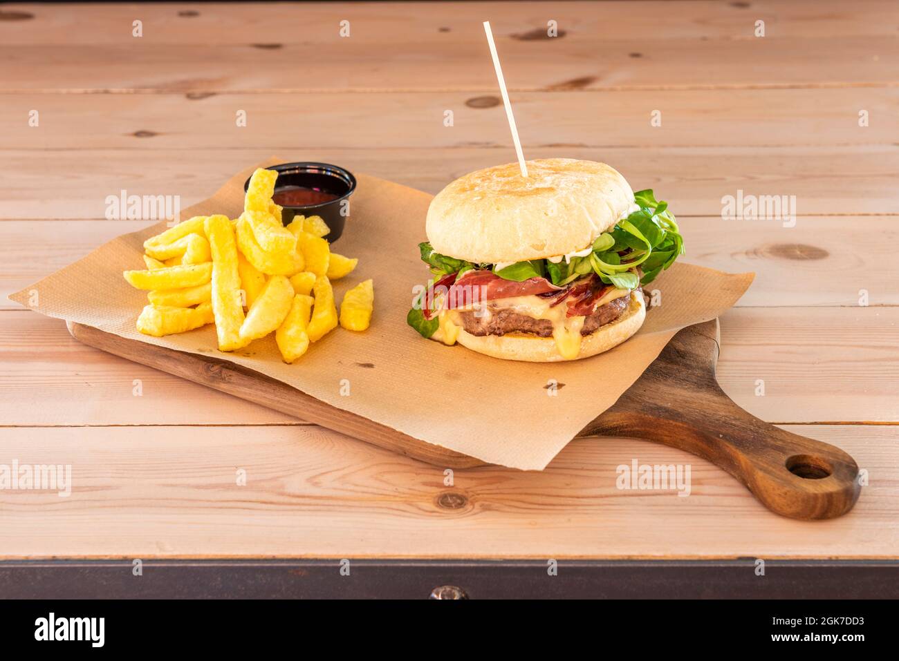 Hamburger di manzo con formaggio fuso, una fetta di prosciutto iberico, lattuga di agnello, maionese e patatine fritte fatte in casa Foto Stock