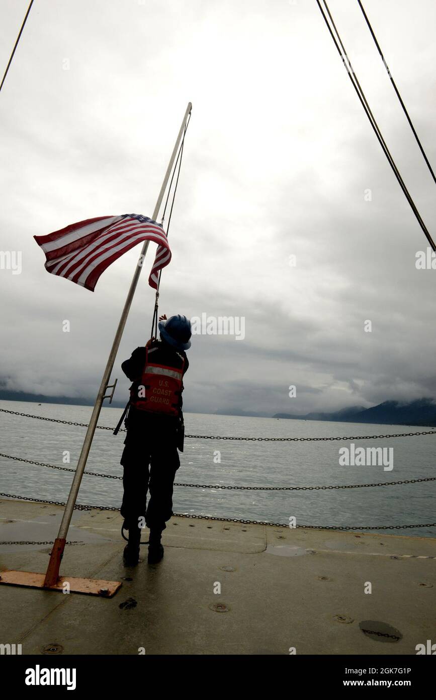 Coast Guard Cutter Healy (WAGB 20) Crewmember Seaman Haley Newell abbattere la bandiera americana come il Healy parte Seward, Alaska, 25 agosto 2021. Durante la loro circumnavigazione del Nord America, Healy e il suo equipaggio condurranno missioni della Guardia Costiera, sosterranno la ricerca oceanografica e promuoveranno gli interessi degli Stati Uniti in tutta la regione. Foto Stock