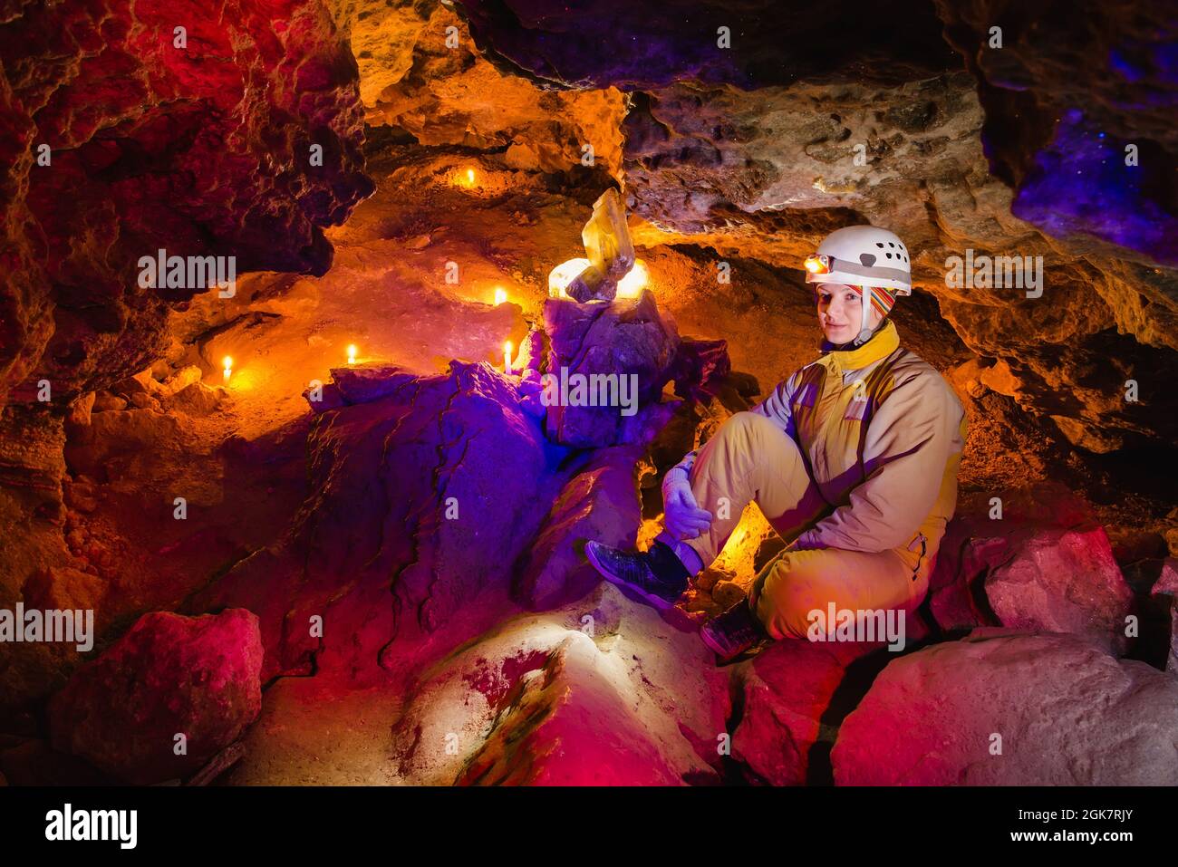 Le donne esplorano la bella grotta di pietra Mlynky in Ucraina. La luce multicolore risplende sulle pietre. Sport estremo attivo. Foto Stock