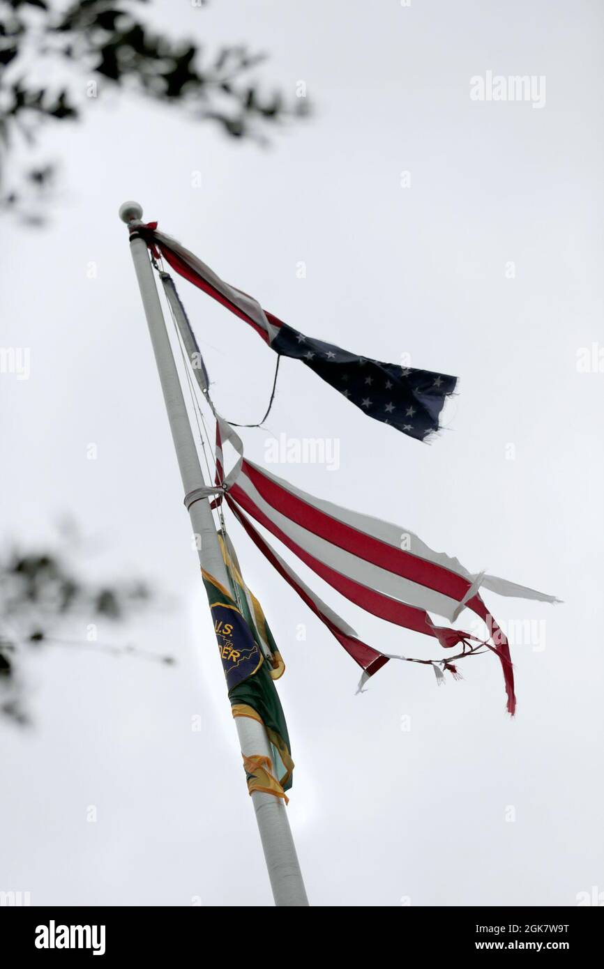 La bandiera degli Stati Uniti e la bandiera della pattuglia di confine degli Stati Uniti colpo tattered nel vento alla stazione di pattuglia di confine degli Stati Uniti a Baton Rouge, la., dopo l'uragano Ida ha saltato attraverso la notte 30 agosto 2021. Foto Stock