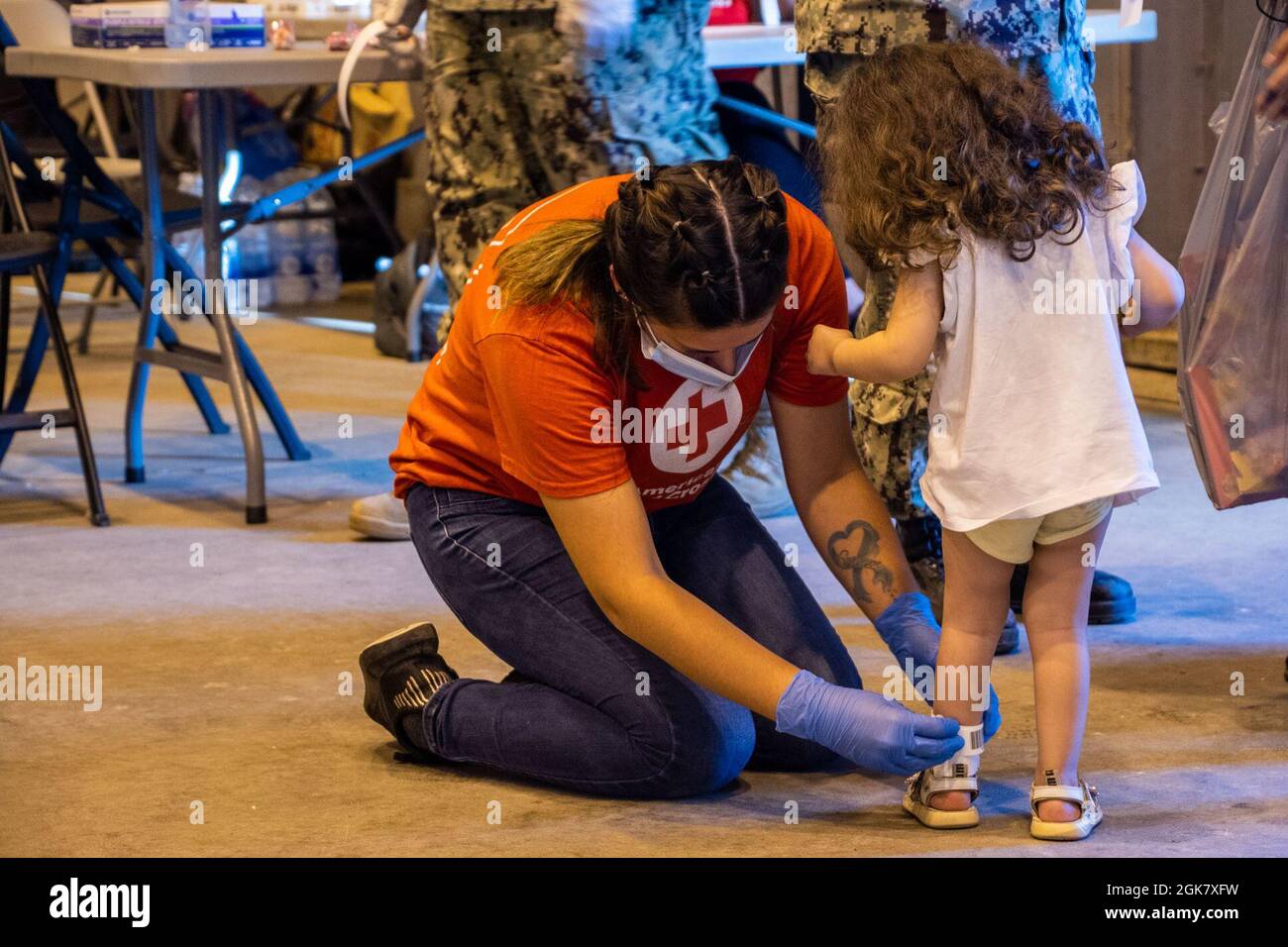 STAZIONE NAVALE ROTA, Spagna (agosto 31, 2021) un volontario della Croce Rossa americana attacca una fascia di identificazione della gamba alla caviglia di un bambino evacuato dall'Afghanistan dopo il suo arrivo alla Stazione Navale (NAVSTA) Rota 31 agosto 2021. NAVSTA Rota sta attualmente sostenendo la missione del Dipartimento di Stato per facilitare la partenza e il trasferimento sicuri dei cittadini degli Stati Uniti, dei beneficiari del visto speciale di immigrazione e delle popolazioni vulnerabili provenienti dall'Afghanistan. Foto Stock