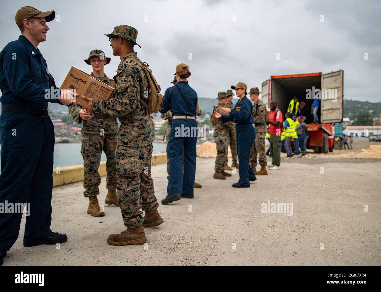 Marines e marinai statunitensi con la Joint Task Force-Haiti (JTF-Haiti) e volontari aiutano a scaricare le scatole per la ridistribuzione nel porto di Jeremie, Haiti, 31 agosto 2021. I Marines e i marinai a bordo della USS Arlington (LPD 24) hanno lavorato a sostegno della JTF-Haiti per una missione di assistenza umanitaria e di soccorso in caso di calamità. Foto Stock