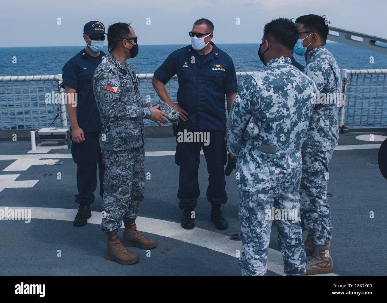 Blake Novak (centro), comandante della Guardia Costiera statunitense Cutter Munro, parla con i membri della Guardia Costiera filippina durante un impegno marittimo il 31 agosto 2021, nel Mare delle Filippine Occidentali. Operando sotto il controllo tattico della 7th flotta degli Stati Uniti, il tagliatore e l'equipaggio stanno effettuando scambi professionali ed esercizi di Capacity-building con le nazioni partner e stanno pattugliando e conducendo le operazioni come indicato. Foto Stock