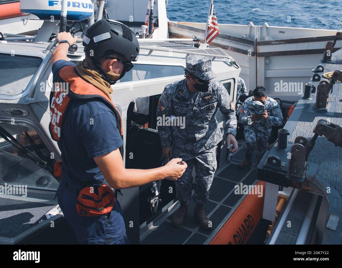 Guardia costiera degli Stati Uniti Petty ufficiale terza classe Westley Sellers, un compagno di boatswains a bordo della Guardia Costiera degli Stati Uniti Cutter Munro, scorts membri della Guardia Costiera filippina a bordo di Munro durante un impegno marittimo 31 agosto 2021, nel Mare delle Filippine Ovest. I membri della Guardia costiera a bordo del Munro sono attualmente dislocati nell'Oceano Pacifico occidentale per rafforzare le alleanze e le partnership e migliorare la governance e la sicurezza marittima nella regione. Foto Stock