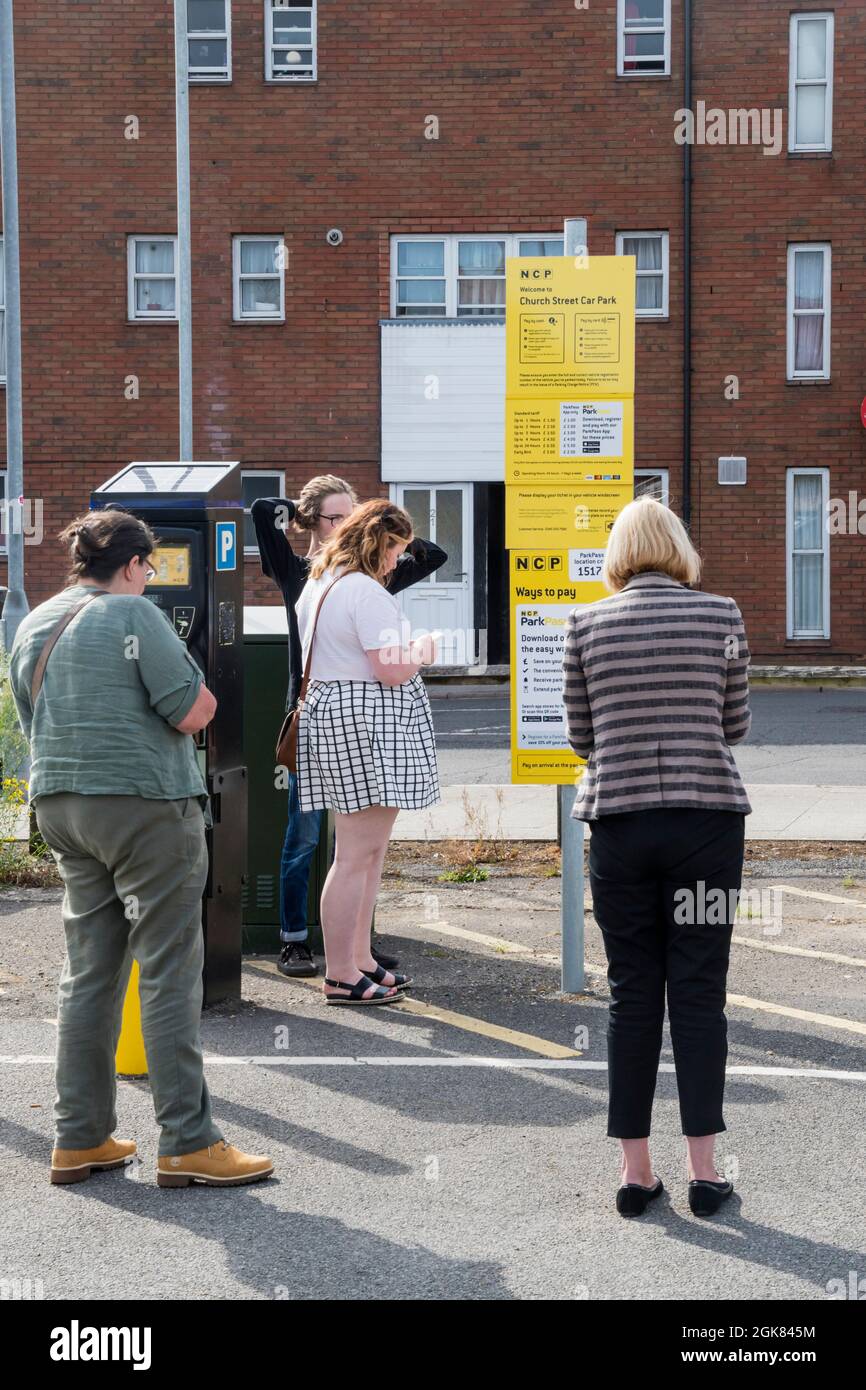 Persone in parcheggio acquistare biglietti per il parcheggio utilizzando carte di credito e telefoni cellulari. Foto Stock
