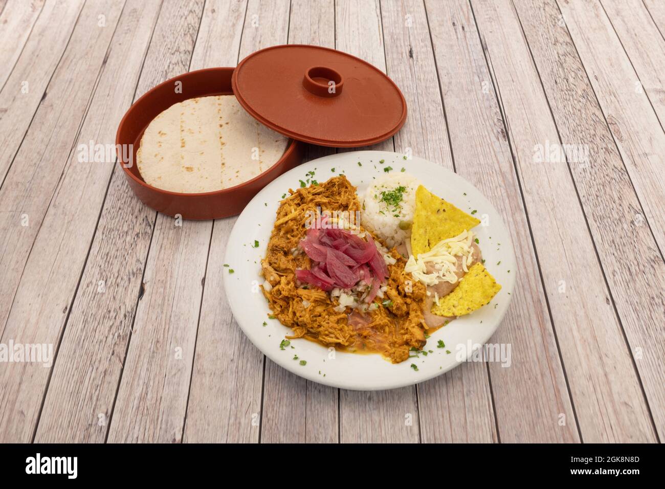 Piatto di stufato di cochinita con riso bianco, formaggio grattugiato, carne di pollo stufato, patatine di mais, prezzemolo fresco tritato e tortillas di grano caldo Foto Stock Piatto di stufato di cochinita con riso bianco, formaggio grattugiato, carne di pollo stufato, patatine di mais, prezzemolo fresco tritato e tortillas di grano caldo Foto Stock