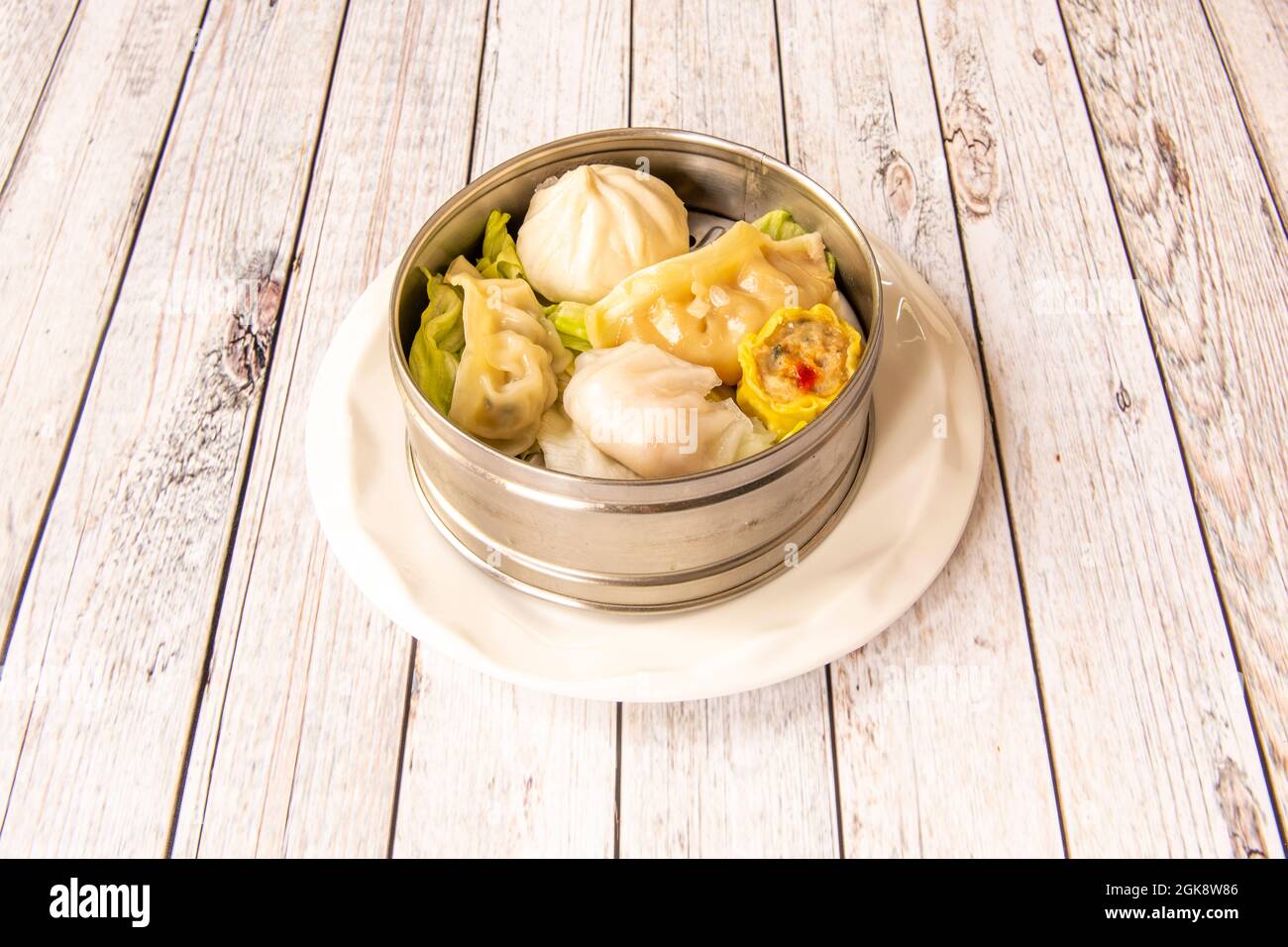 Dim sum e gyozas al vapore assortiti cucinati da uno chef cinese in una ciotola di metallo Foto Stock