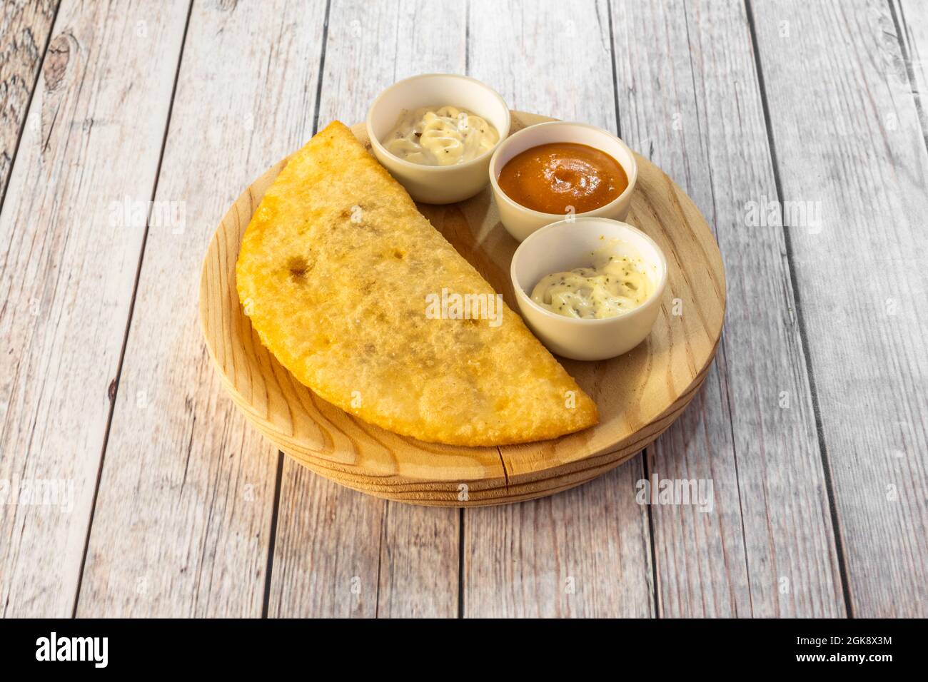 grande patina gialla di farina di mais farcita con carne di pollo con salse da immersione su piatto di legno non verniciato Foto Stock