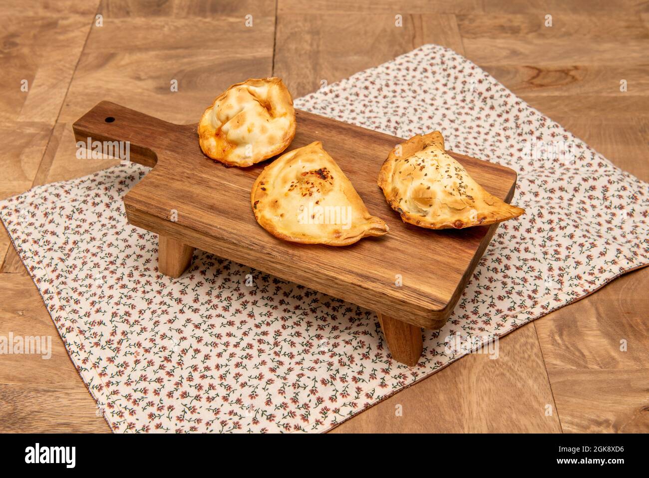 Empanadas di vari sapori preparati con ricette argentine su tavola di legno con gambe Foto Stock